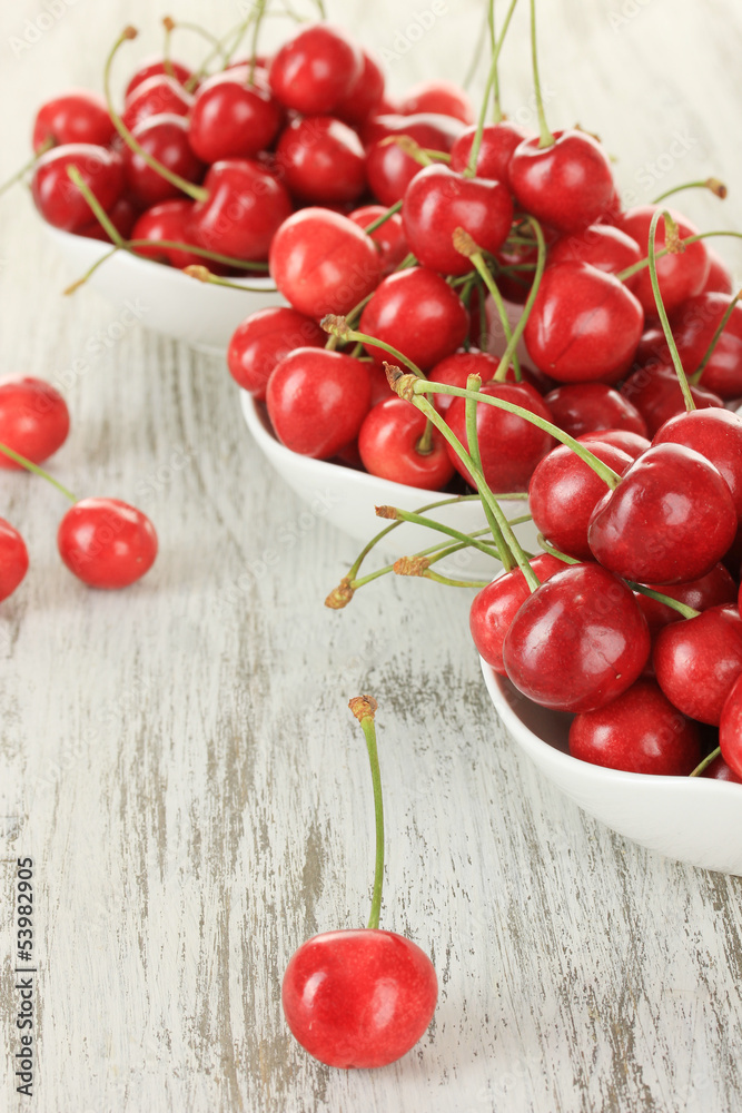 Cherry berries in bowl on wooden table close up Cherry berries in bowl on wooden table close up