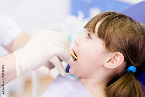 dental examining being given to little girl by dentist