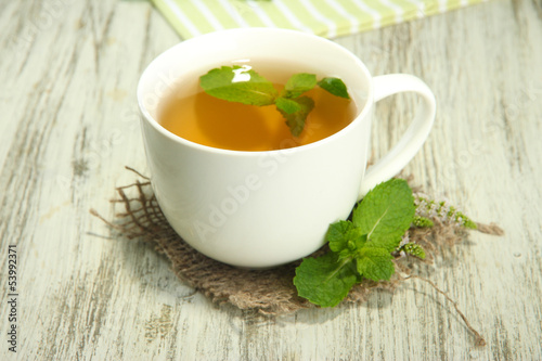 \cup of herbal tea with fresh mint on wooden table