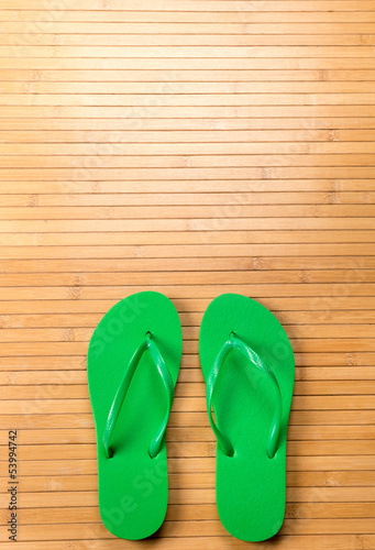 Green Flip Flops on Bamboo Mat With Copy Space