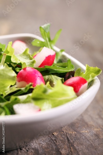 Bowl with various lettuce leaves and radishes