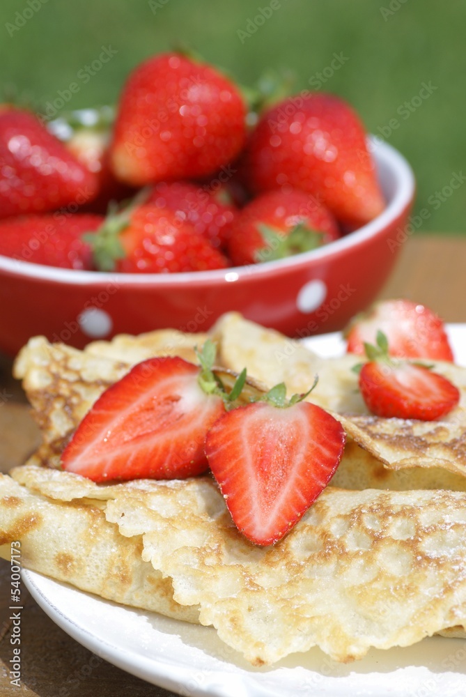 Sweet crepes with strawberries on garden table. Sweet crepes with strawberries on garden table.