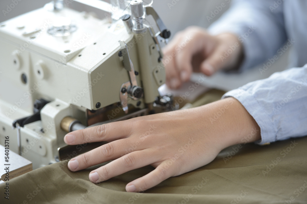 Closeup on dressmaker hand using sewing machine