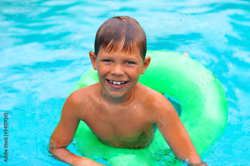 Smiling boy swims in pool on summer vacations