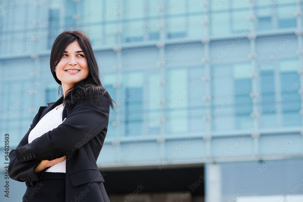 Smiling entrepeneur crossing her arms in front of a office build Smiling entrepeneur crossing her arms in front of a office build