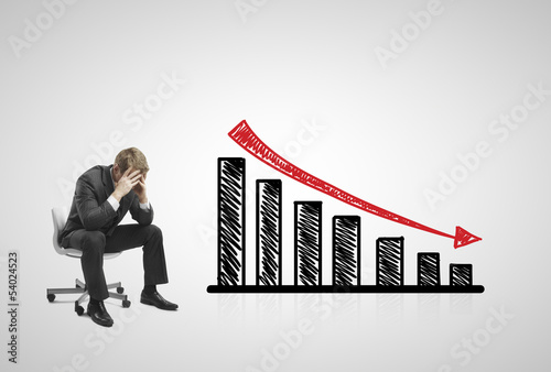 sad businessman sitting on chair with falling  chart photo