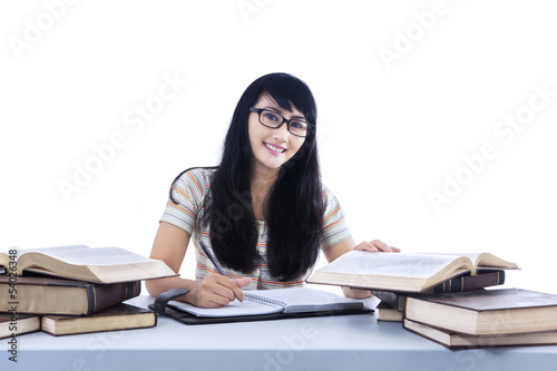 Beautiful female student writing book - isolated