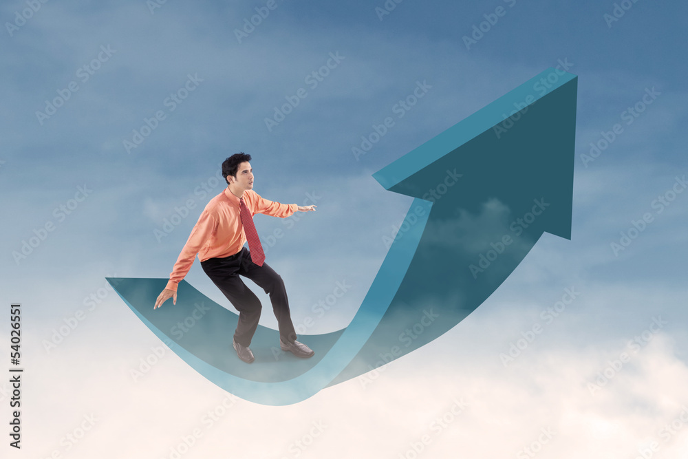 Fototapeta premium Businessman riding arrow sign in the sky