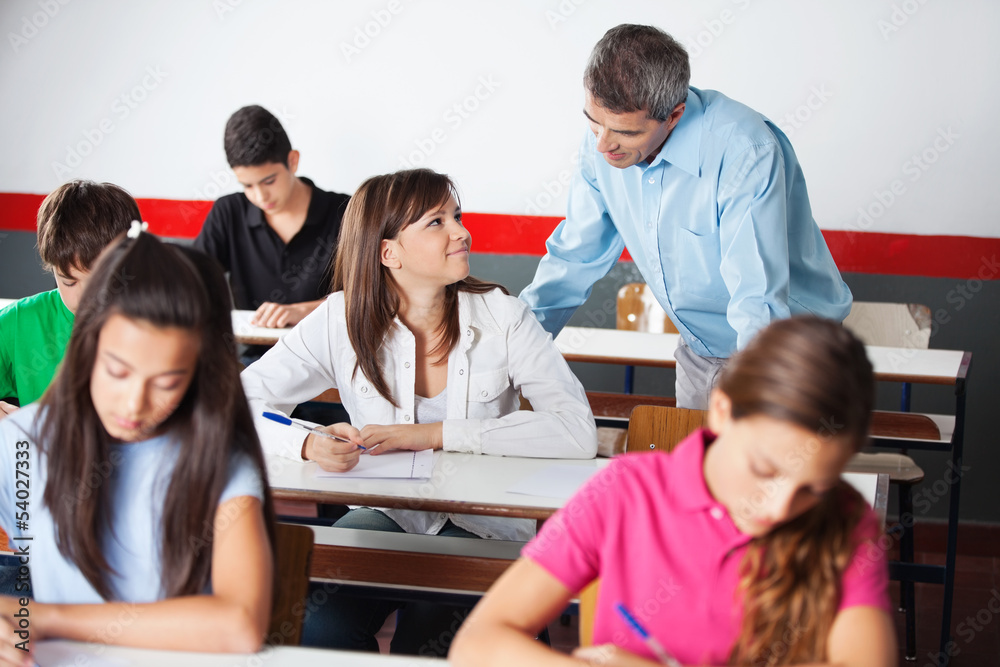 Teacher And Teenage Girl Looking At Each Other During Examinatio Teacher And Teenage Girl Looking At Each Other During Examinatio
