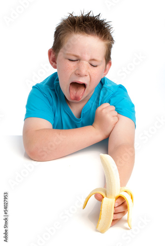Photography Yound boy not happy about eating a banana.