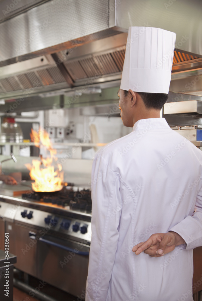 Chef with Fingers Crossed as a Pan Catches Fire Chef with Fingers Crossed as a Pan Catches Fire