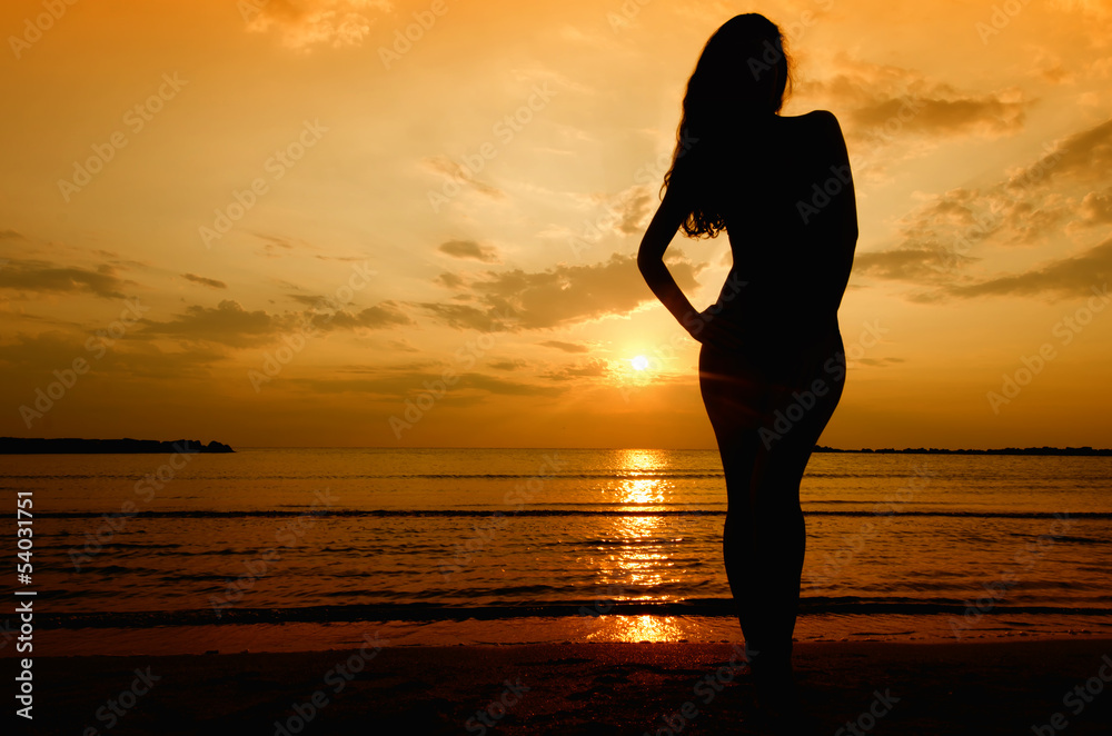 Silhouette of a sensual woman at sunrise on the beach