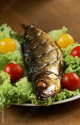 Smoked fish on plate with lettuce and tomatoes.
