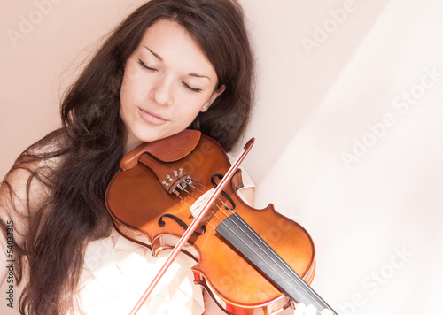 Portrait of a pretty young female playing the violin.