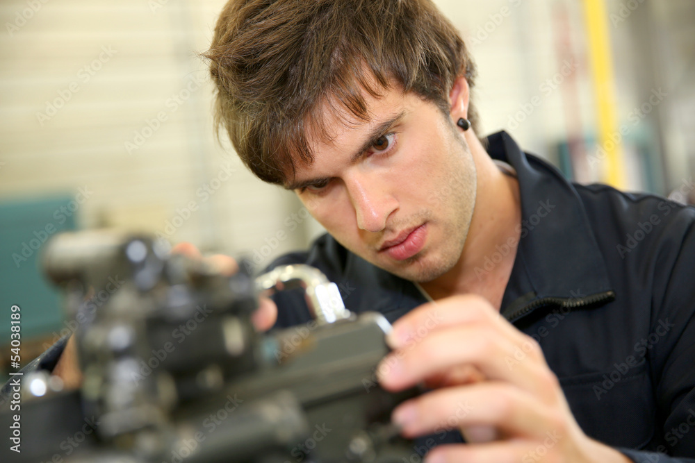 Teenager in professional training, repairing bike engine Teenager in professional training, repairing bike engine