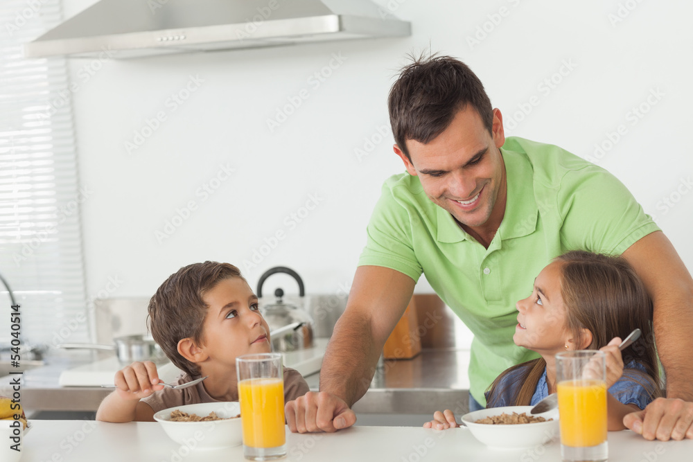 Father talking to his children while they are having breakfast Father talking to his children while they are having breakfast