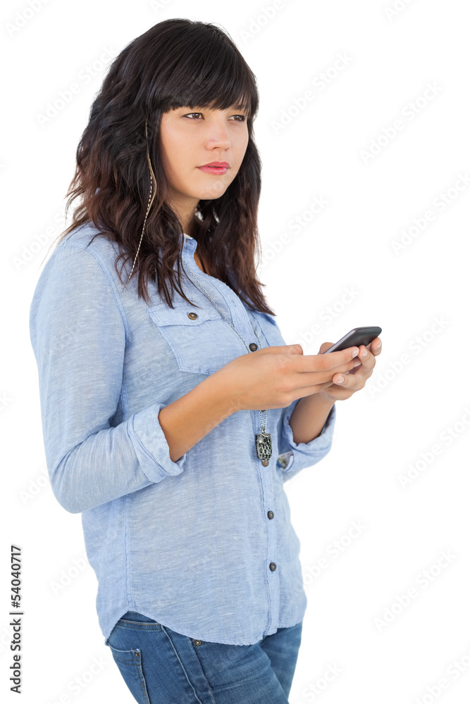 Thoughtful brunette with her mobile phone texting a message Thoughtful brunette with her mobile phone texting a message