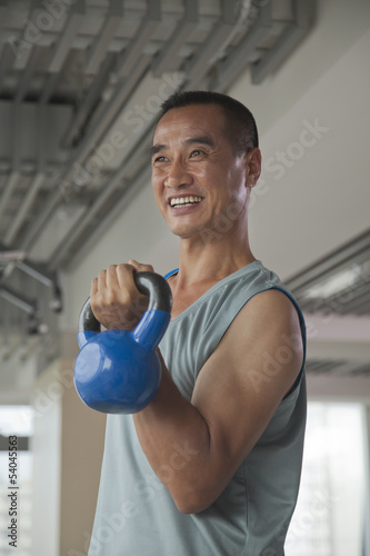 Mature man lifting weights in the gym