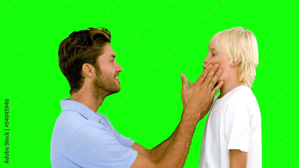Man pressing inflated cheeks of his son on green screen Man pressing inflated cheeks of his son on green screen