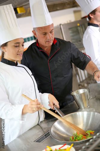 Chef teaching student how to prepare wok dish