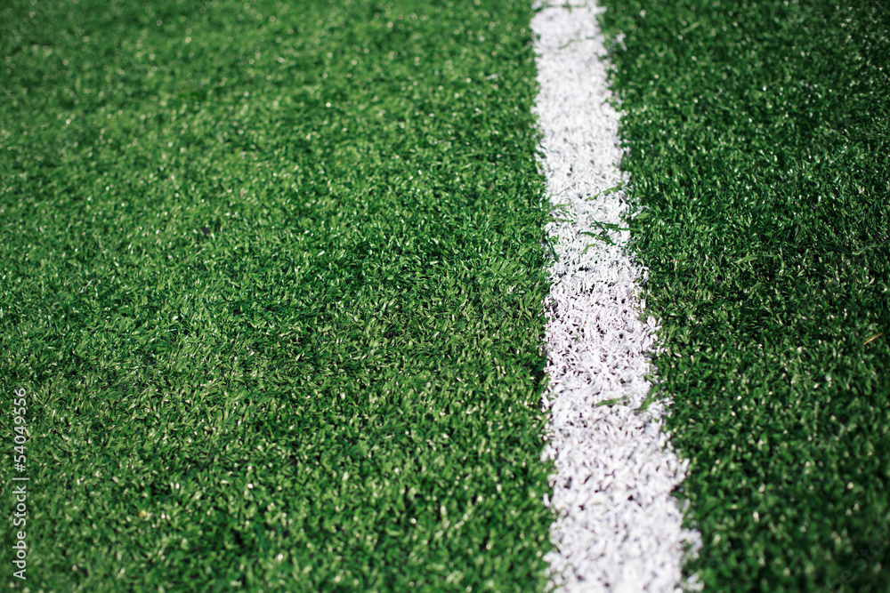 Fototapeta premium White stripe on the green soccer field from top view