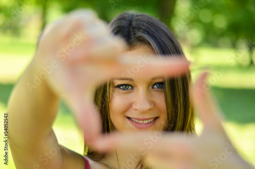 Beautiful girl making frame with hands while outdoors