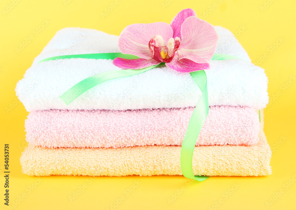 Towels tied with ribbon on yellow background Towels tied with ribbon on yellow background