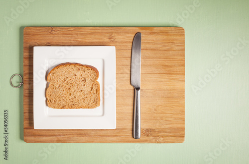 Sliced brown bread on square white plate with knife