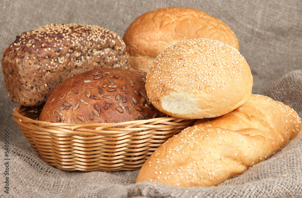 Baked bread in wicker basket on burlap background Baked bread in wicker basket on burlap background