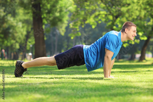 Young handsome sportsman exercising in a park