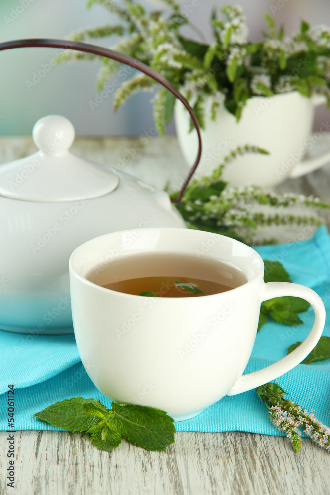 Teapot and cup of herbal tea with fresh mint flowers Teapot and cup of herbal tea with fresh mint flowers