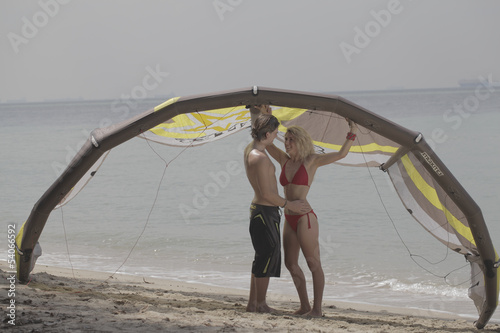 A couple on the beach in swimwear, kitesurfing