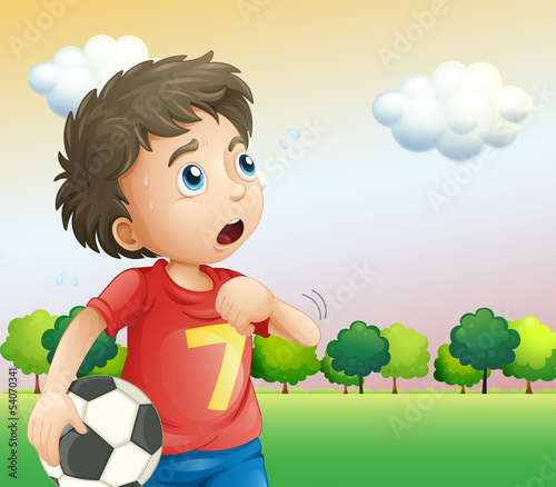 A boy holding a soccer ball wearing a red shirt