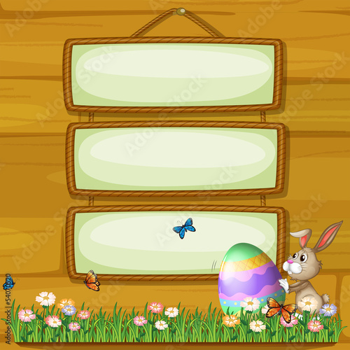 A bunny pushing an egg in front of the hanging signage photo