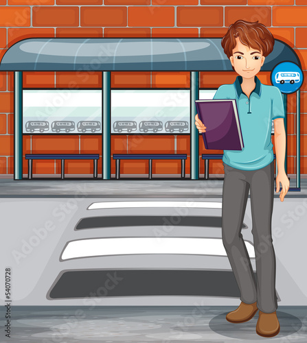 A man holding a book near the bus stop