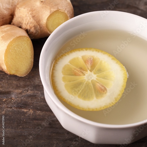 Cup of ginger tea and fresh ingredients - ginger and lemon.