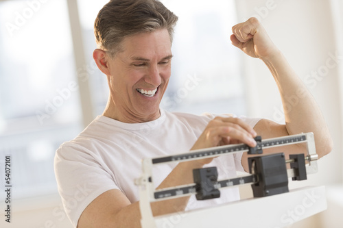 Excited Man Clenching Fist While Using Weight Scale