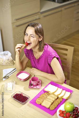 Happy beautiful woman having breakfast eating strawberry