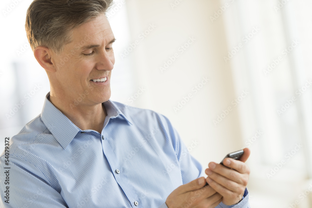 Businessman Smiling While Messaging Through Mobile Phone Businessman Smiling While Messaging Through Mobile Phone