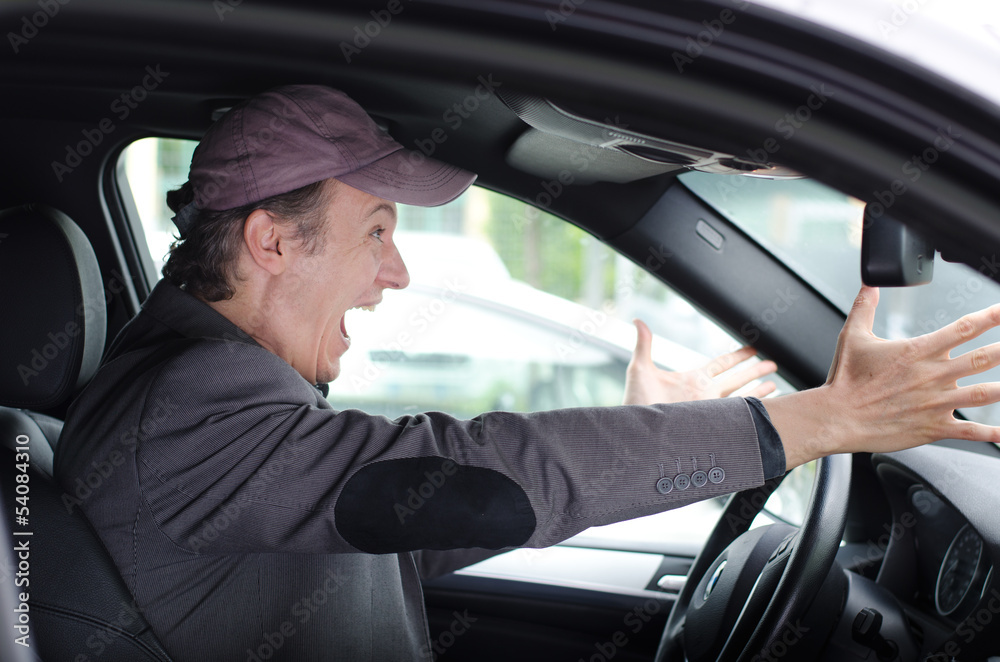 Angry upset man at wheel driving his car screaming