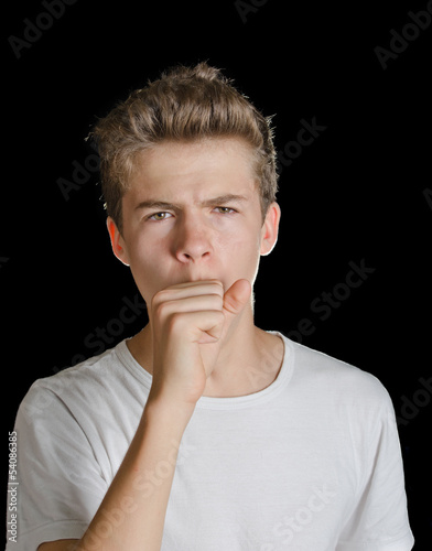 Cute teenager boy coughing, isolated on black