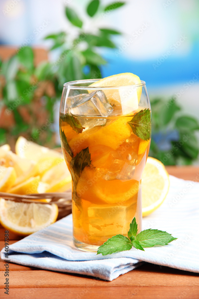 Iced tea with lemon and mint on wooden table, outdoors Iced tea with lemon and mint on wooden table, outdoors