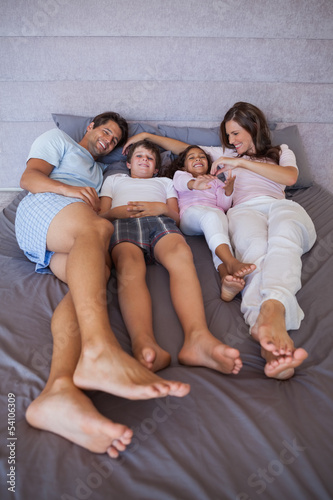 Happy family lying together on bed © WavebreakmediaMicro