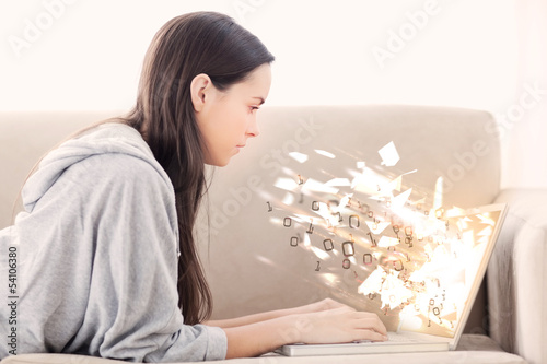 Woman using laptop with binary codes exploding over