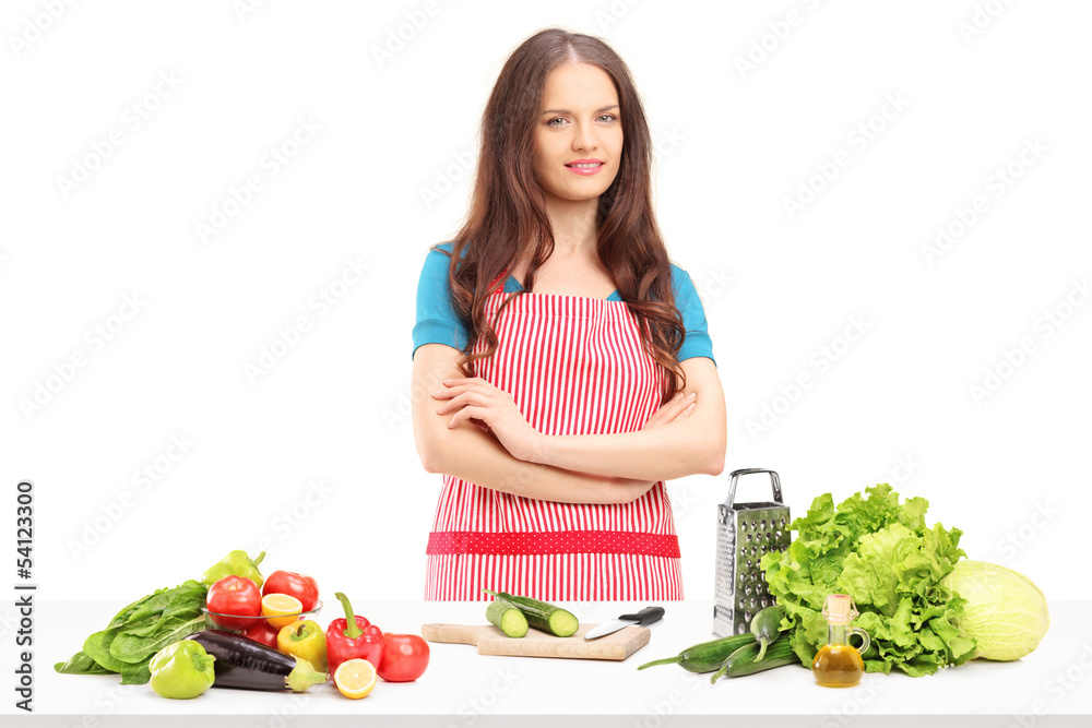 Young smiling housewife with apron preparing salad
