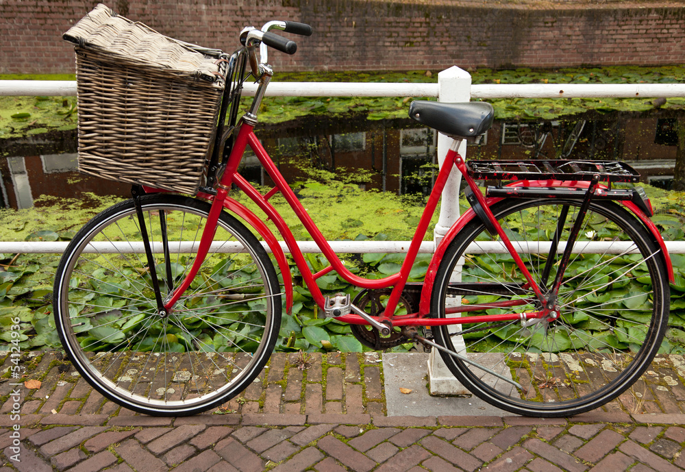 Red Bicycle with Basket Parked Beside Canal in Holland