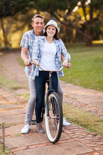 teenage couple riding bicycle together