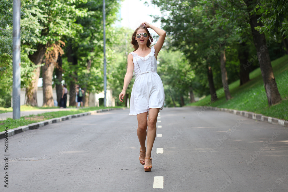 Beautiful young woman walking on the summer park
