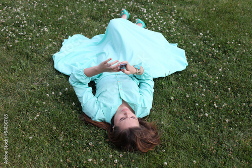Young woman lying on the grass with phone in hand