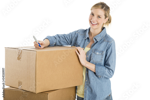 Beautiful Woman With Pen Standing By Stacked Cardboard Boxes photo